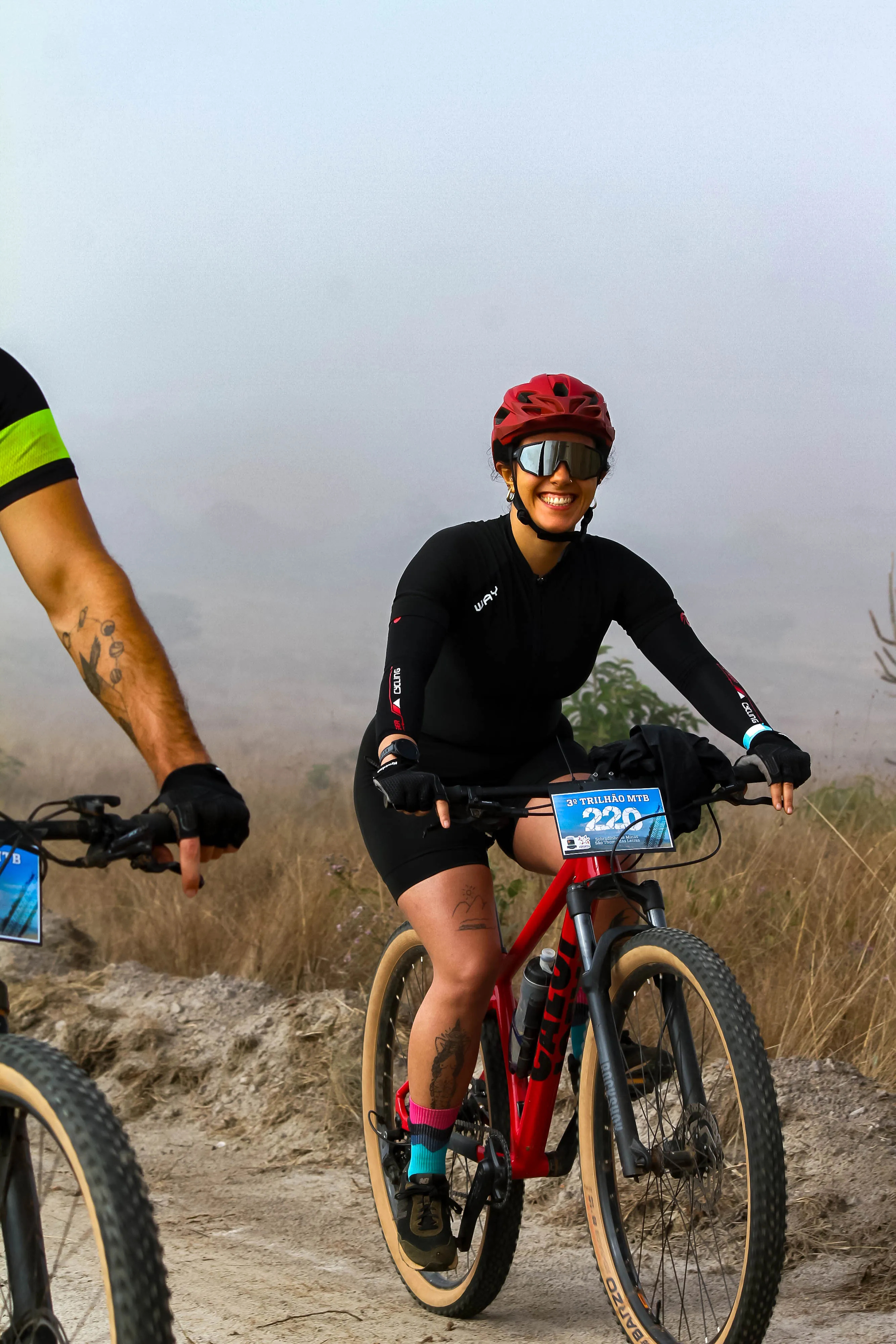 Ciclista sorrindo com capacete vermelho durante o percurso
